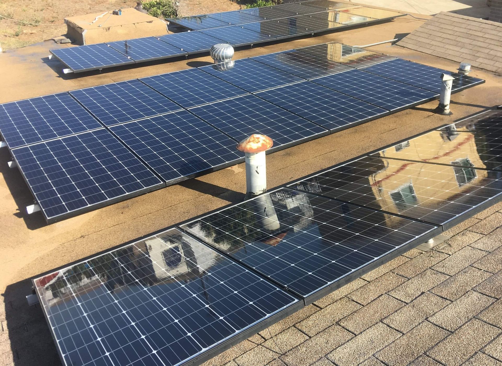 Solar panels installed on a tan rooftop with vents and skylights.