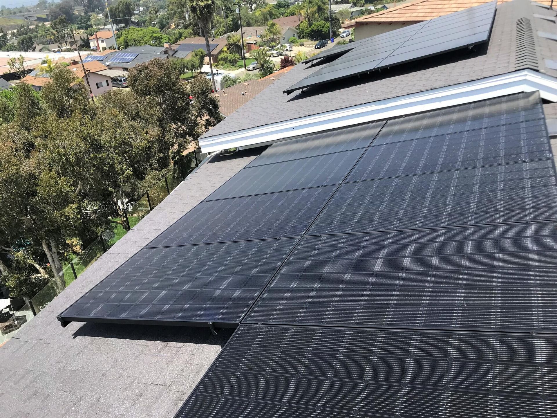 Rooftop solar panels on a house overlooking a leafy neighborhood on a sunny day