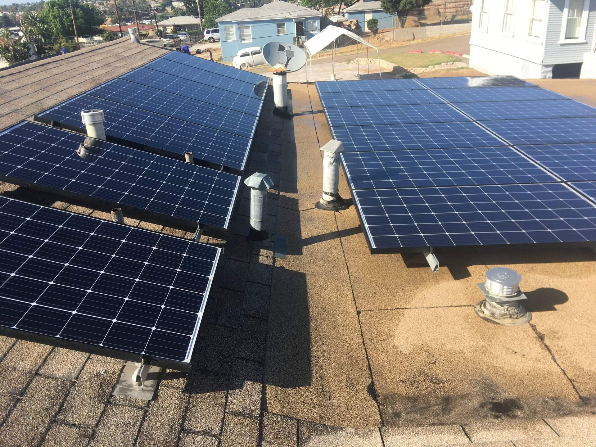 Rows of blue solar panels on a tan rooftop under bright sunlight