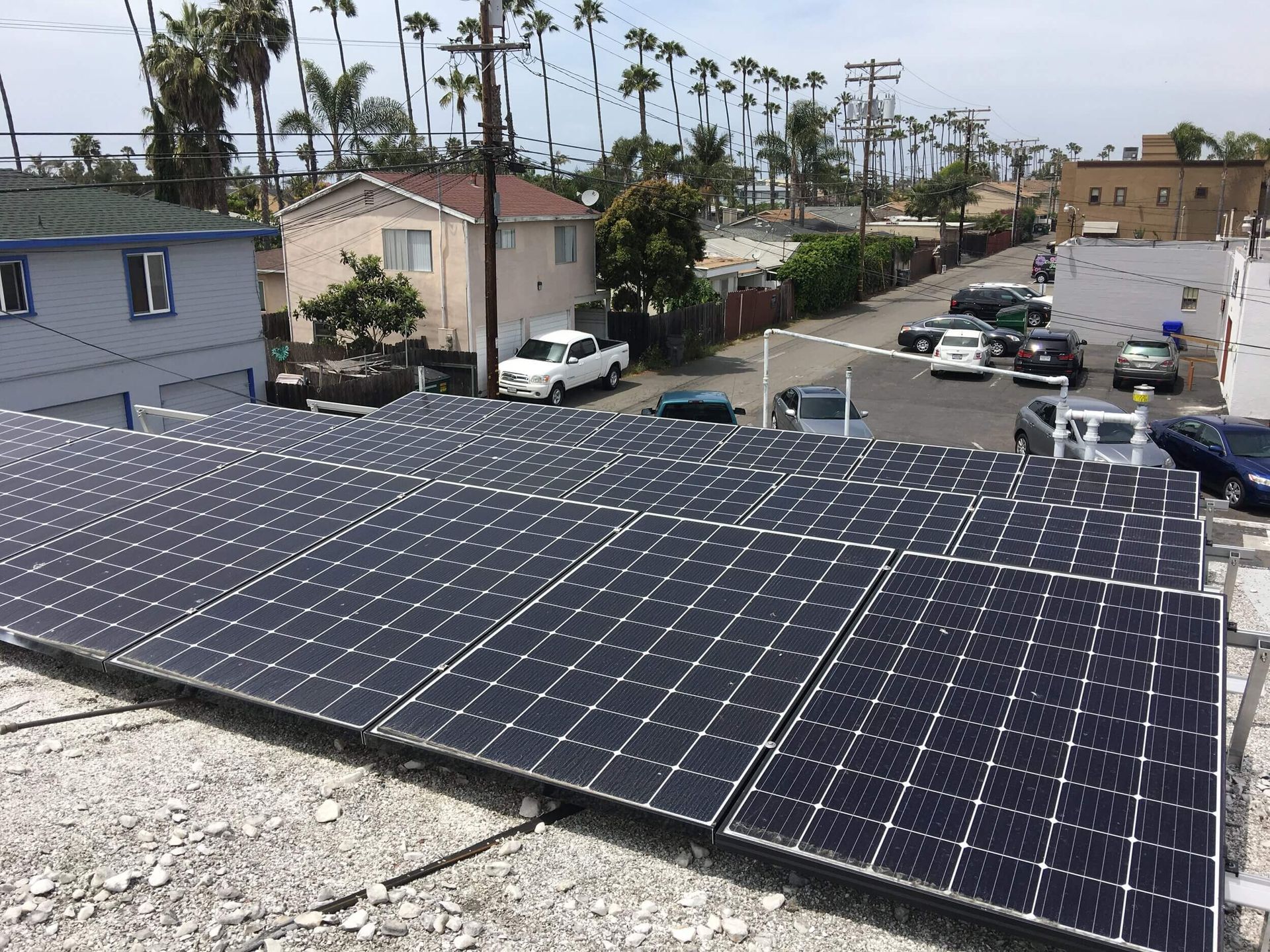 Solar panels on a rooftop overlooking a coastal neighborhood and street under a cloudy sky