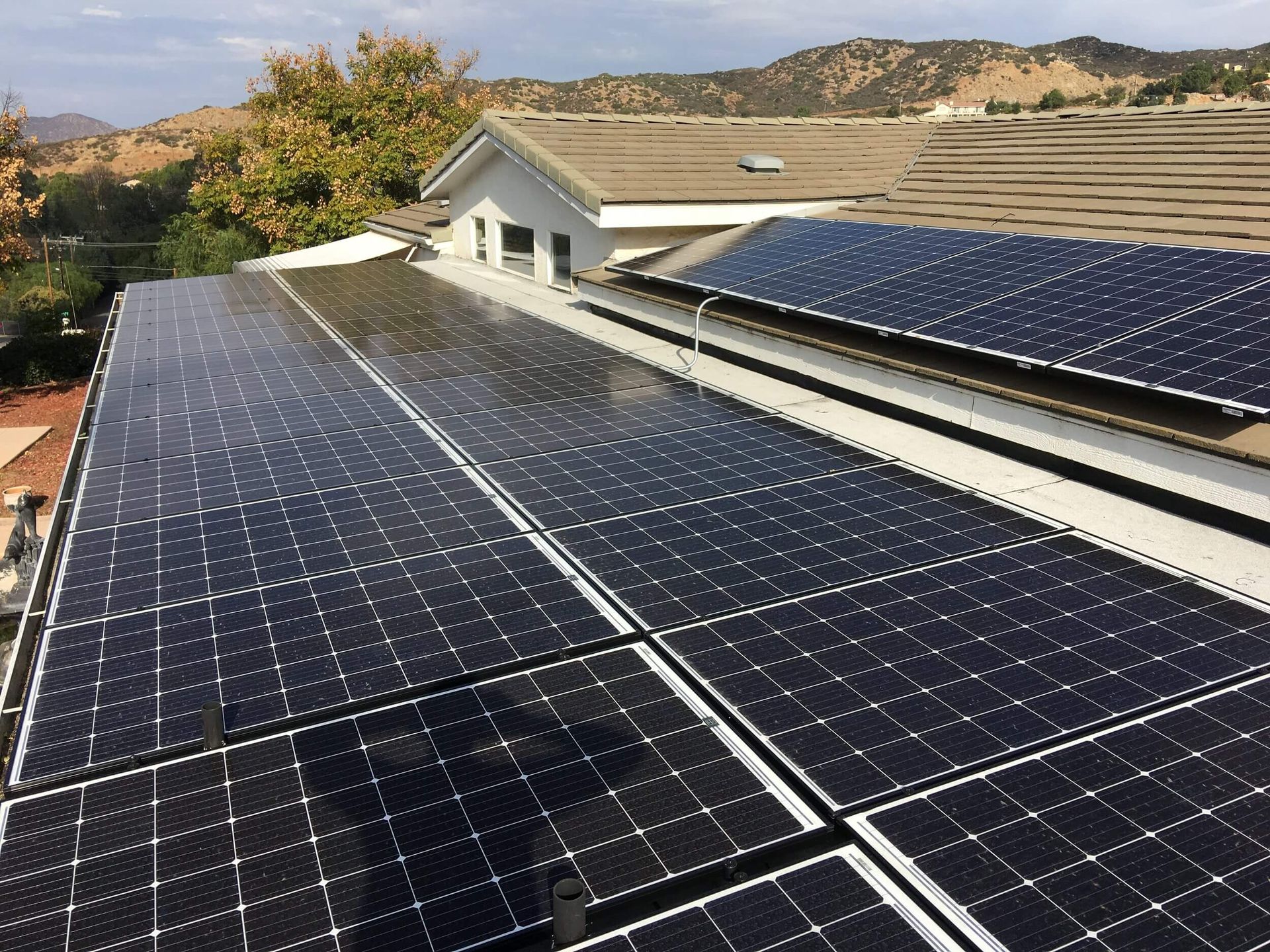 Solar panels covering a house roof with hills in the background