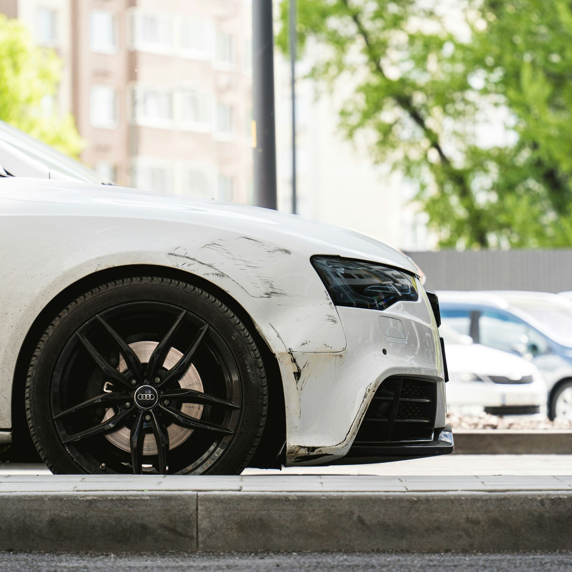 Side view of a white car with a scratch on the wheel arch.