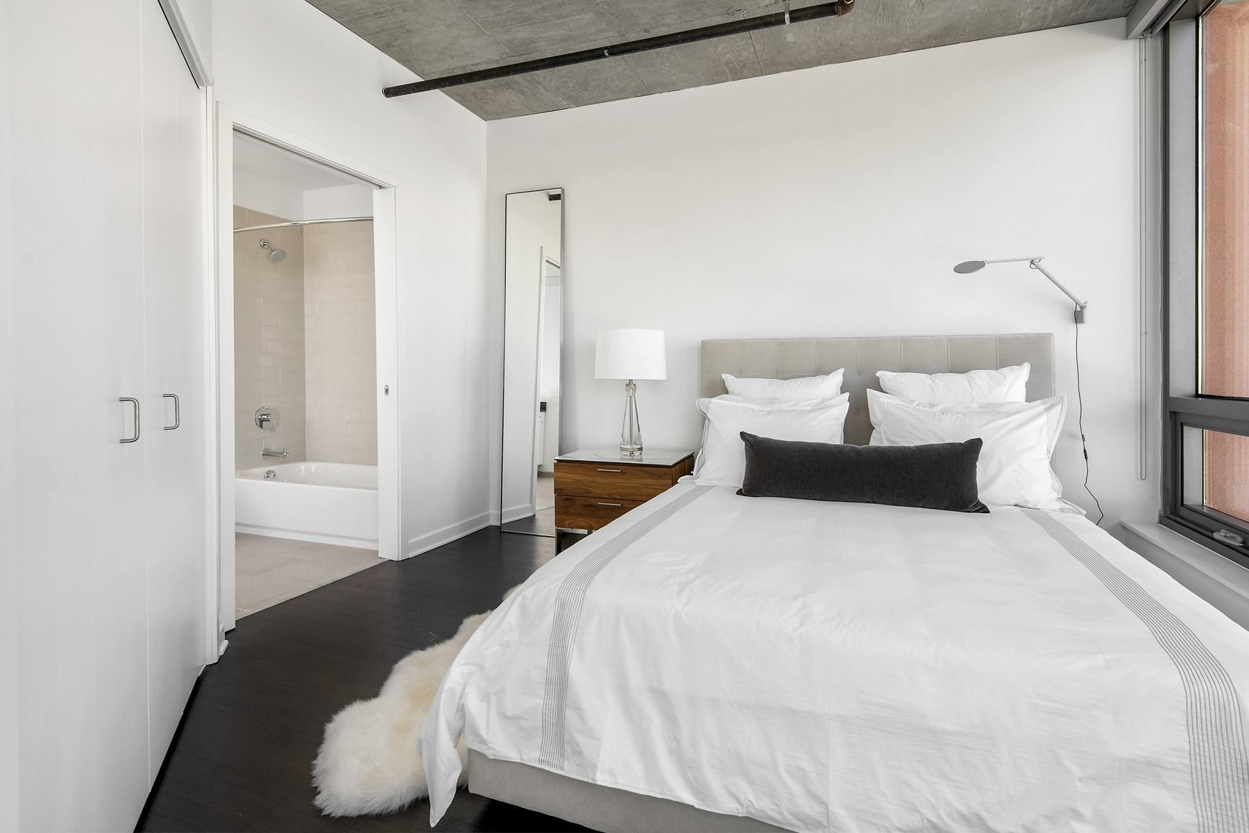 a bedroom with a white bed and a large window
