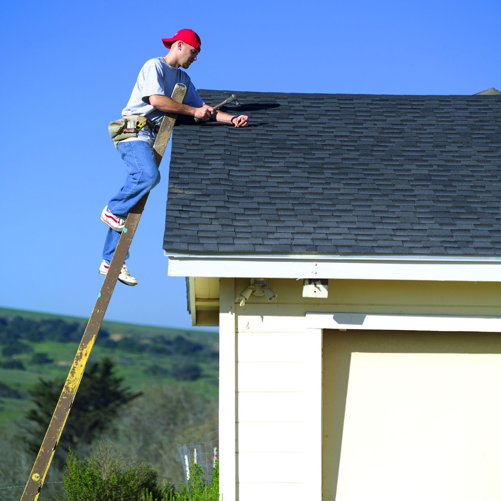 A man on a ladder working on a roof in Utica, NY, representing Upstate Home Improvements, expert roo