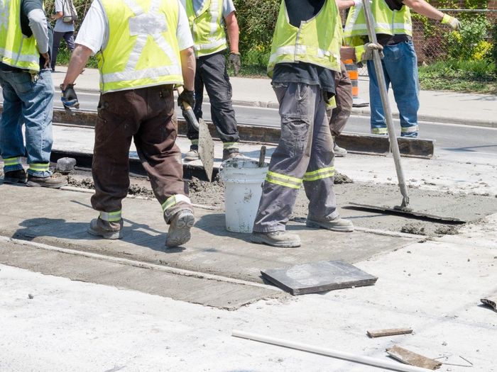 A group of construction workers are working on a road.