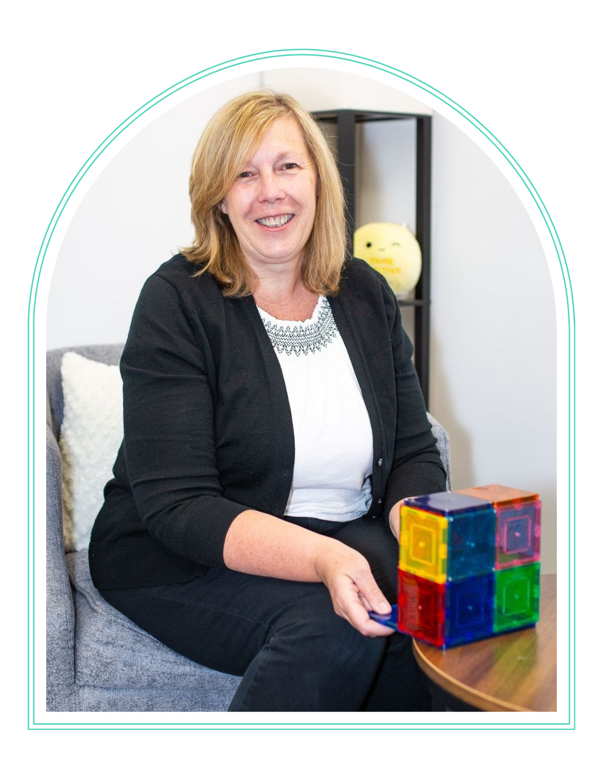 a woman sits in a chair with a stack of magnets on a table