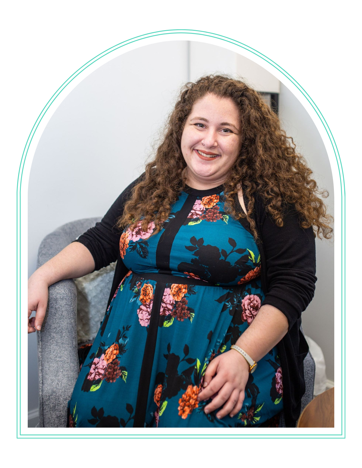 a woman in a floral dress sits in a chair