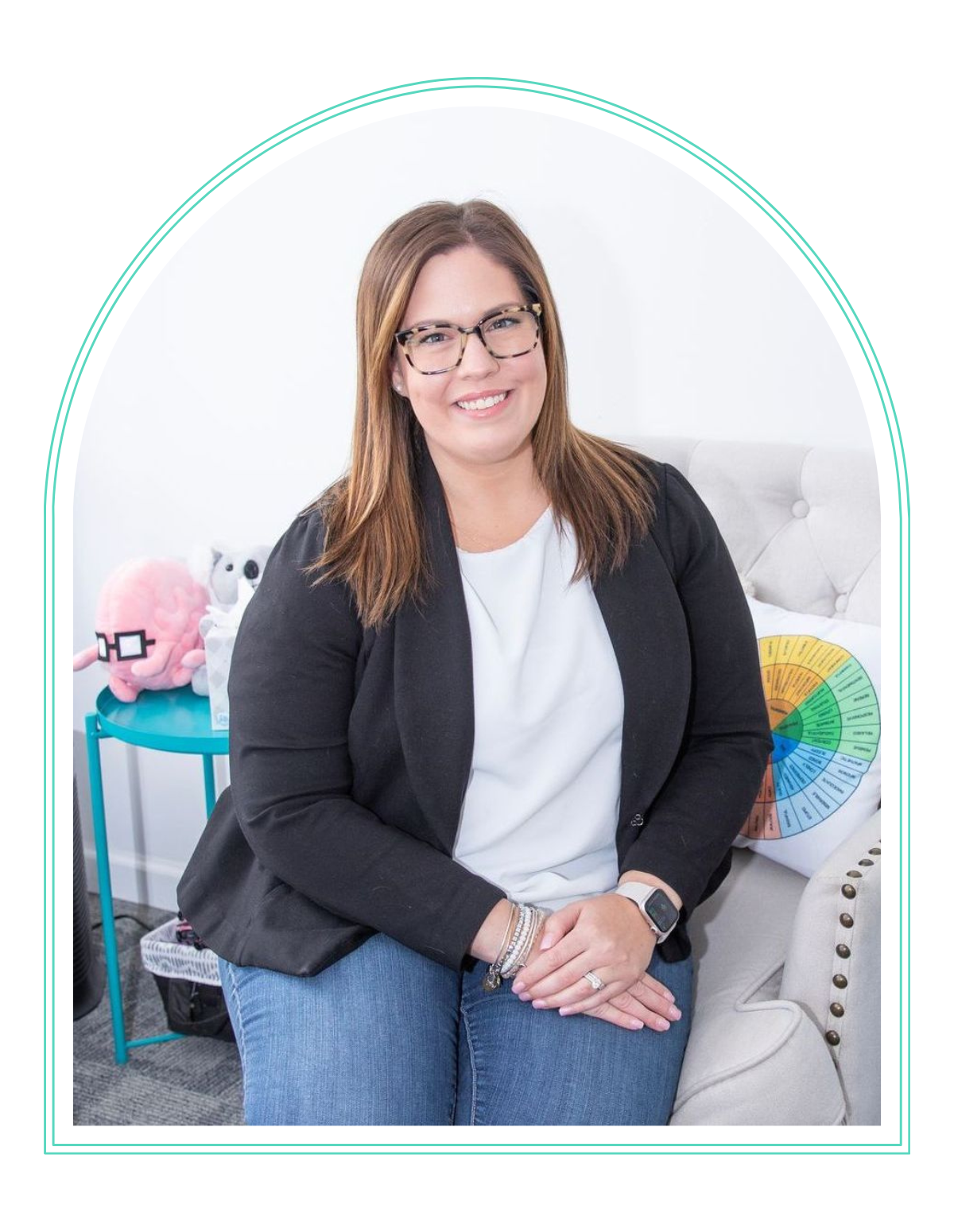 a woman wearing glasses and a black jacket sits on a couch