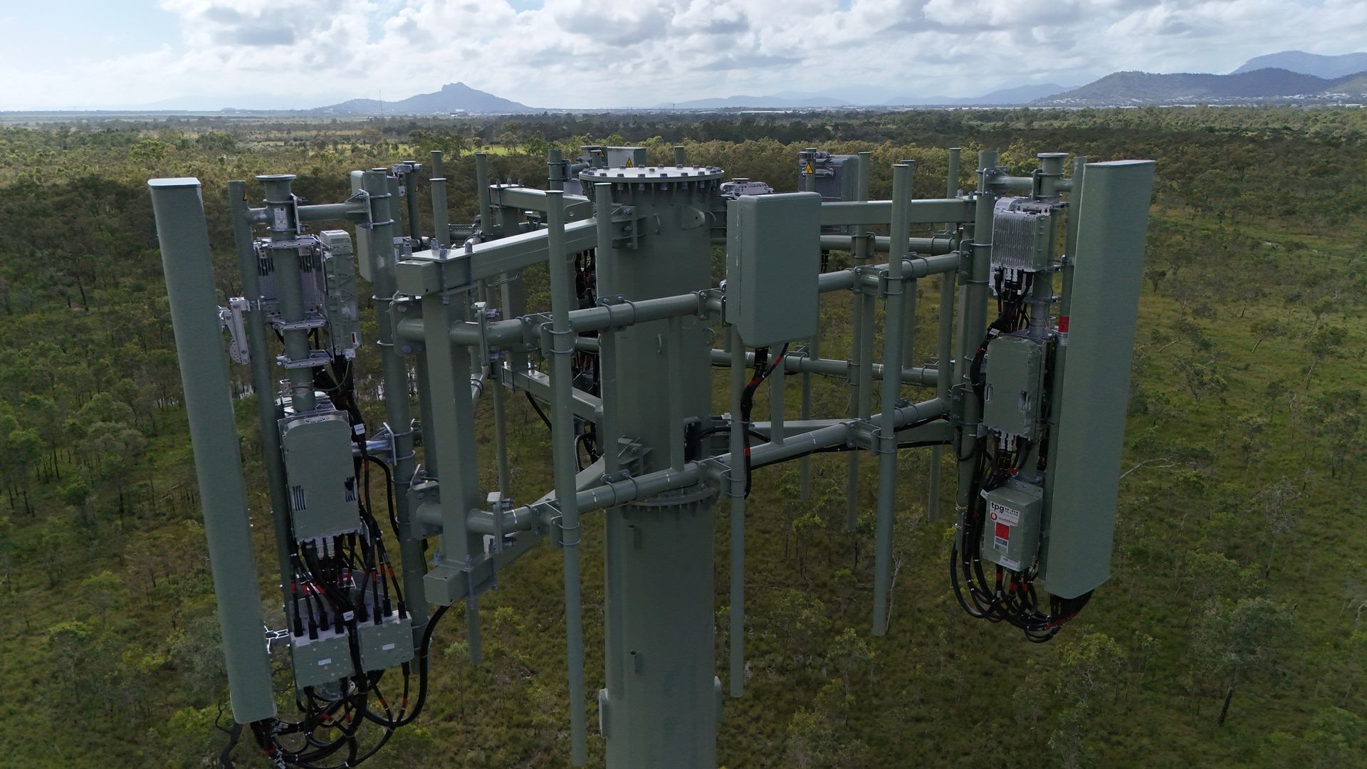 Row of gray telecom antennas and equipment on a grassy field under a cloudy sky — UAScend Aerial Solutions in Townsville, QLD