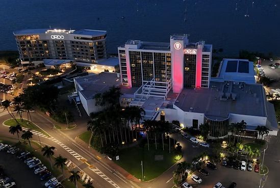 Nighttime aerial view of a lit hotel or resort complex beside a road and palm trees — UAScend Aerial Solutions in Townsville, QLD