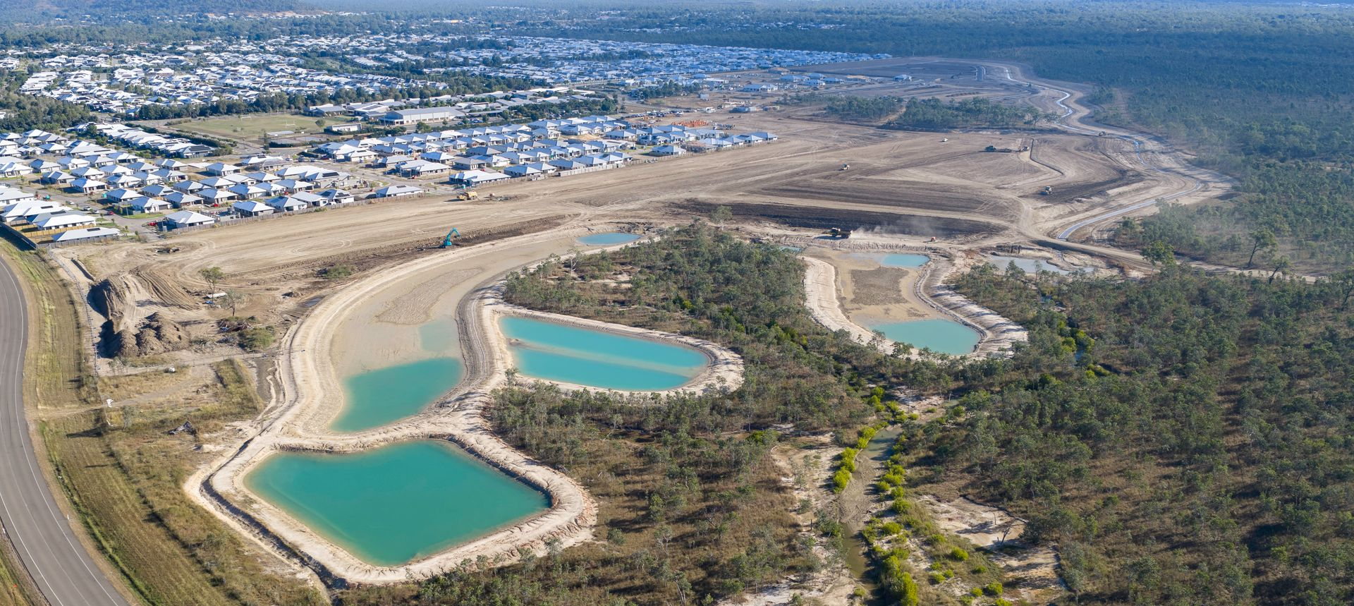 Aerial view of three turquoise ponds beside a forest and a suburban neighborhood. — UAScend Aerial Solutions in Townsville, QLD