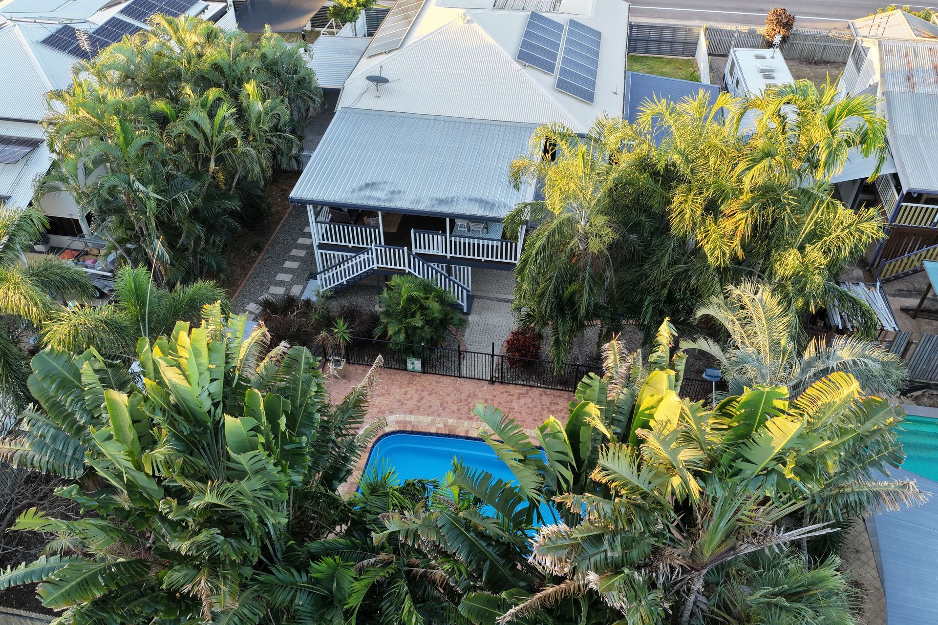 Aerial view of a tropical home with a pool, palm trees, and solar panels on the roof — UAScend Aerial Solutions in Townsville, QLD.