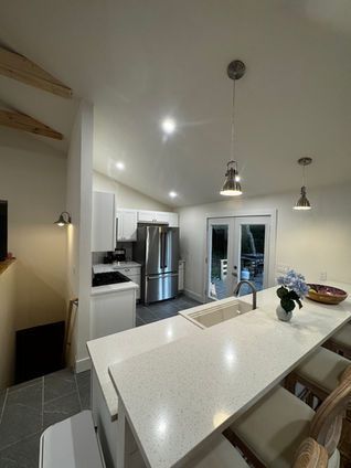 Bright, modern kitchen with white cabinets, stainless steel appliances, and a quartz countertop island.