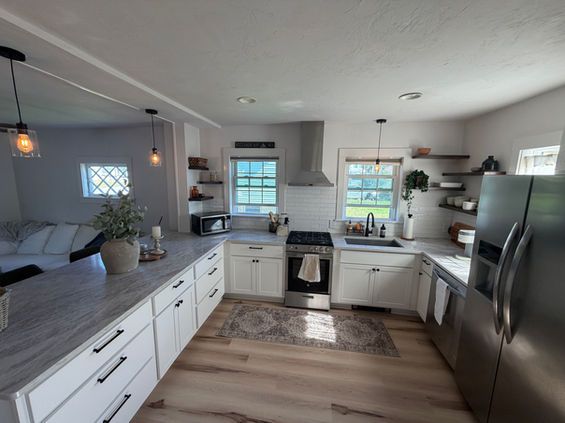 Bright kitchen with white cabinets, stainless steel appliances, and wood-look flooring.