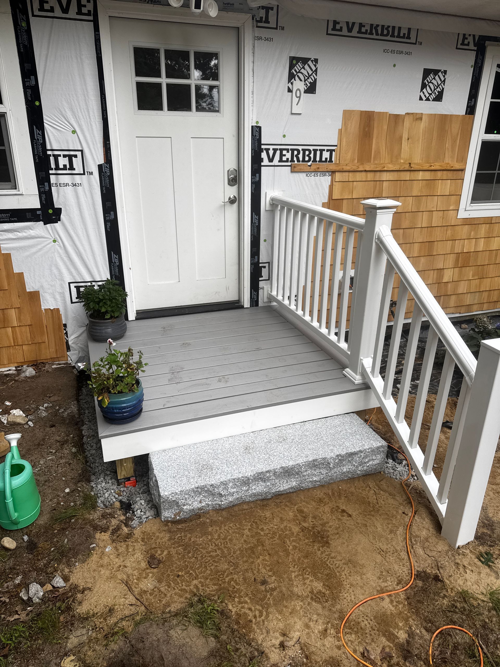 White door with small porch, steps and railing under construction.