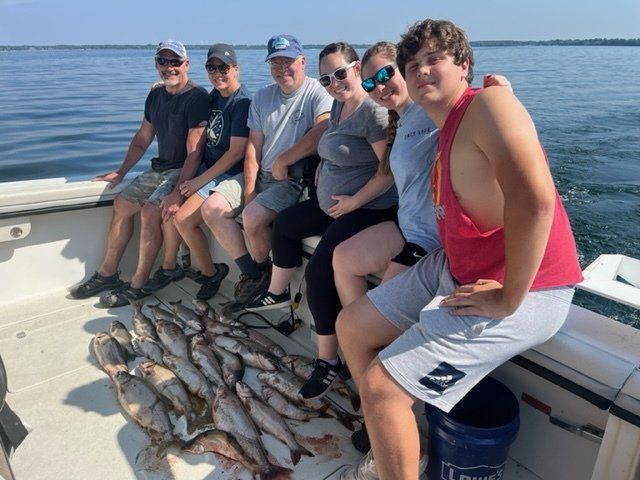A group of people are sitting on a boat with lots of fish