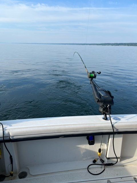 A fishing rod is attached to the side of a boat in the ocean.