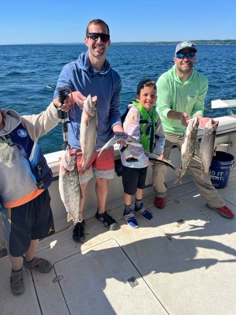 A group of people are standing on a boat holding fish.