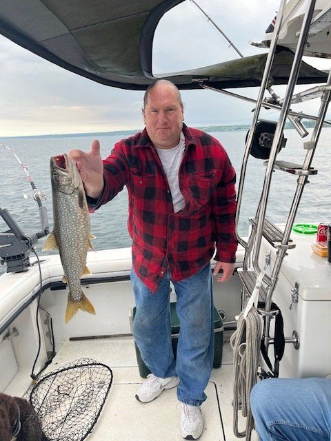 A man in a plaid shirt is holding a fish on a boat