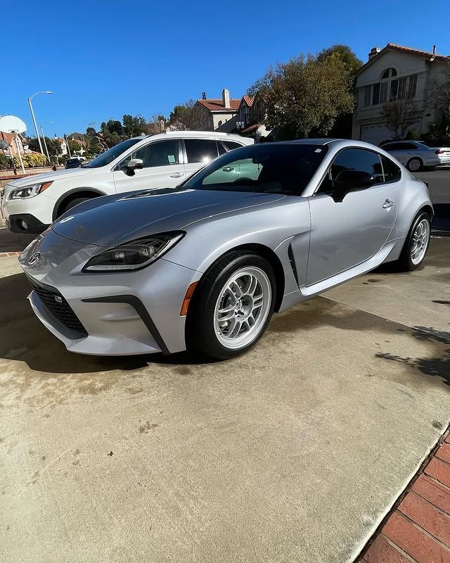 A silver sports car is parked in a parking lot next to a white suv.