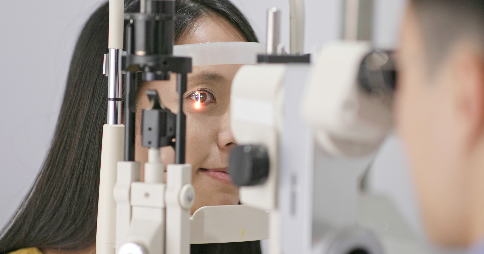 Woman having an eye exam with an optometrist using a slit lamp microscope