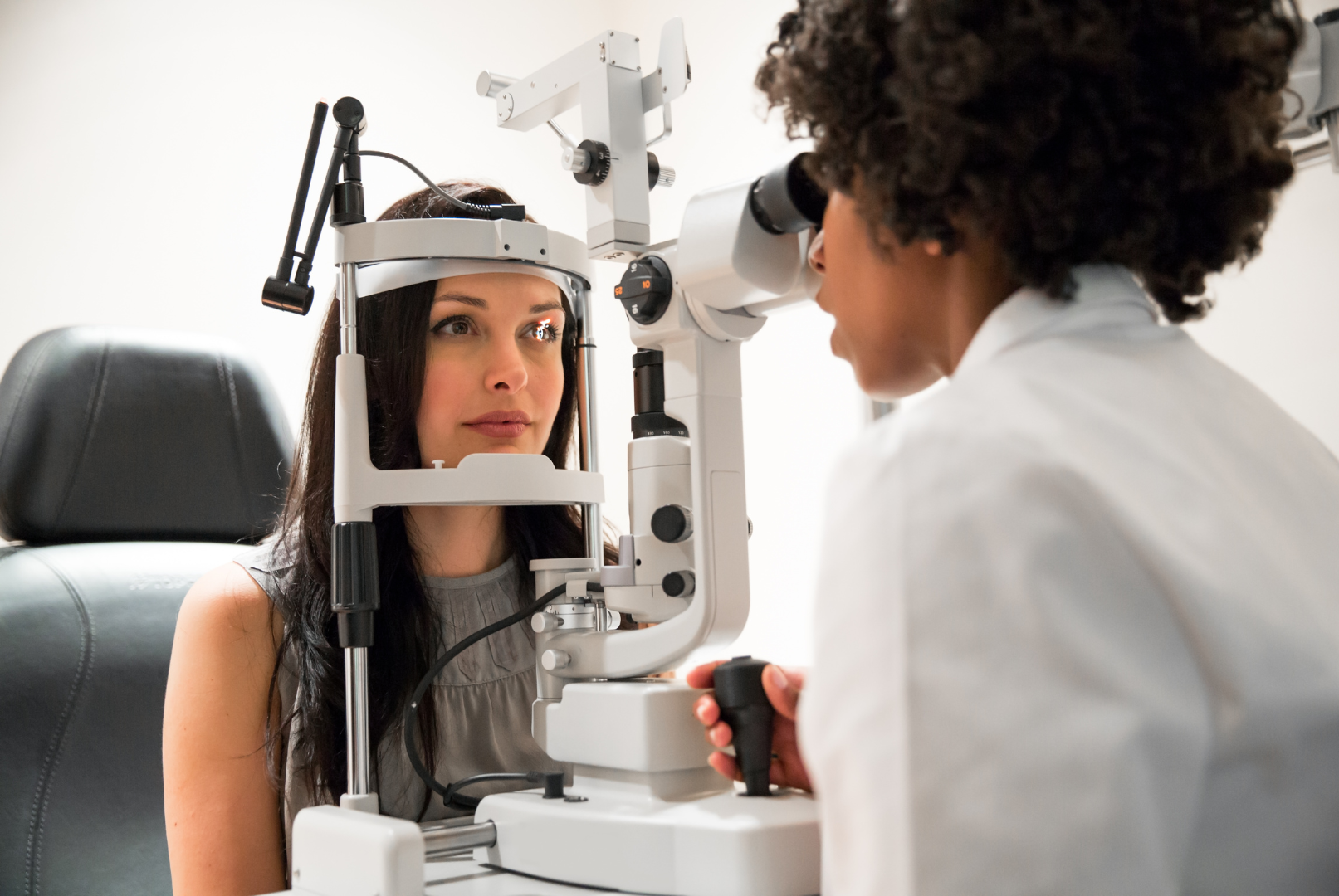 Eye exam with optometrist examining a patient at a slit lamp microscope