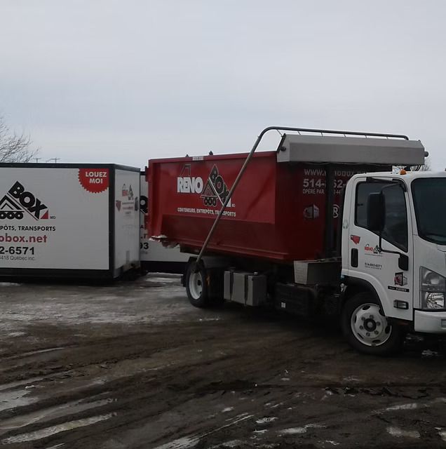 Un camion de rénovation rouge est garé à côté d'une boîte blanche