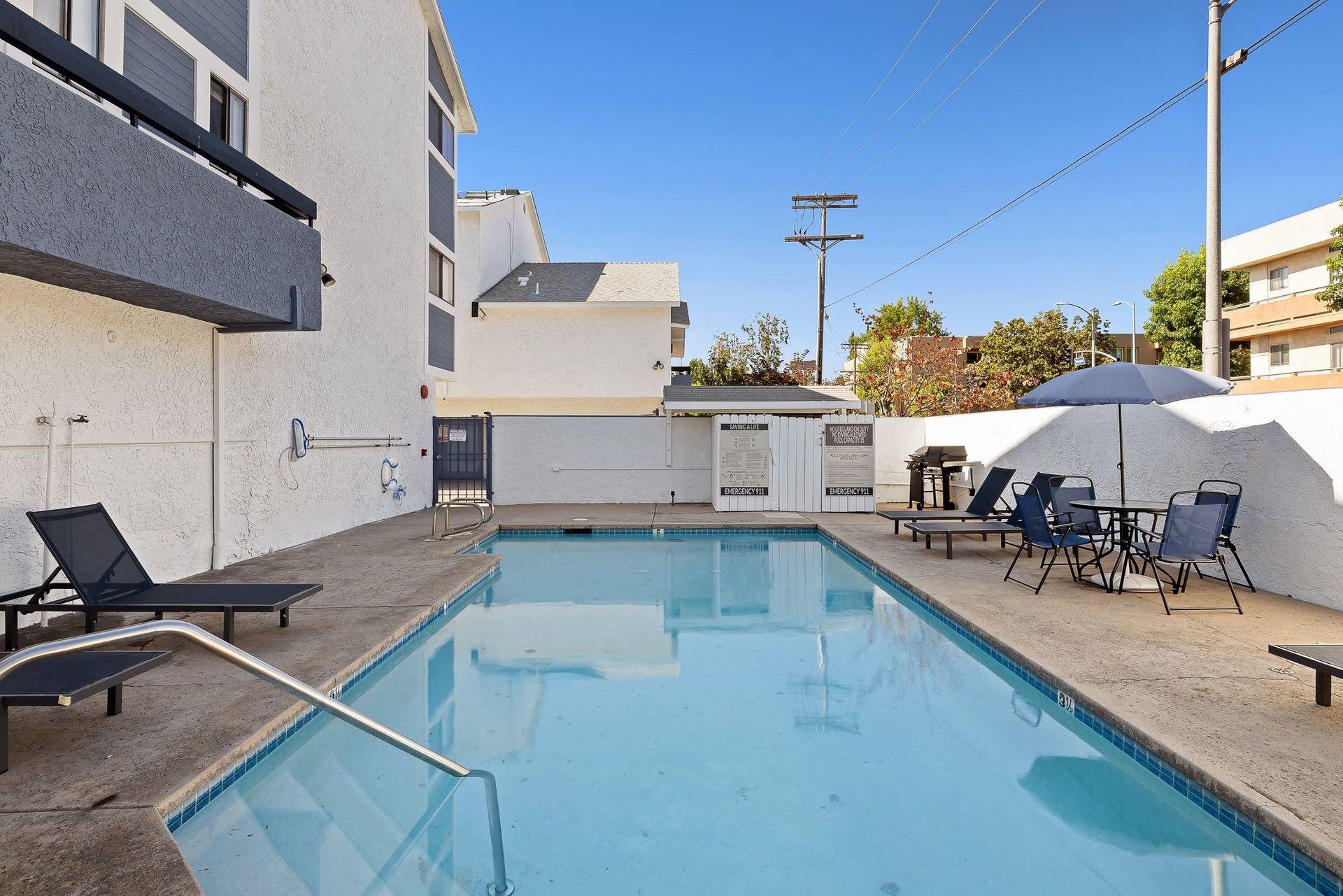 Outdoor swimming pool surrounded by lounge chairs and umbrellas on a sunny day