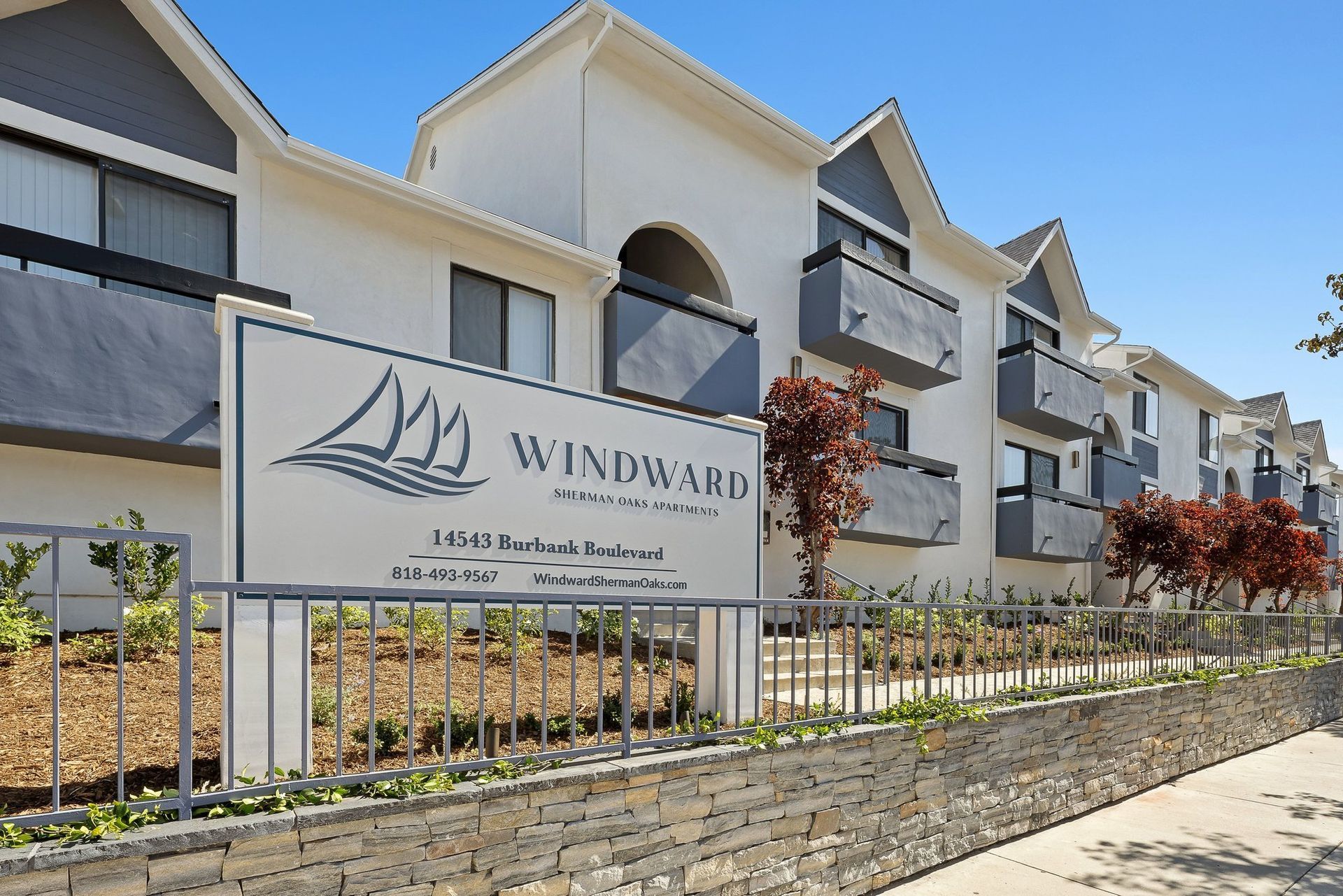 Windward apartment complex sign in front of beige townhomes on a sunny day