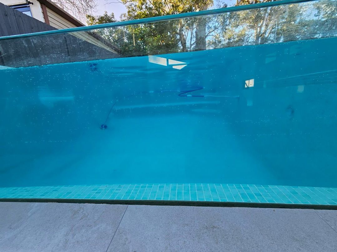 A Clear, Turquoise-water-filled Swimming Pool With a Glass Side Wall — All Glass Balustrading Systems in Wetherill Park, NSW