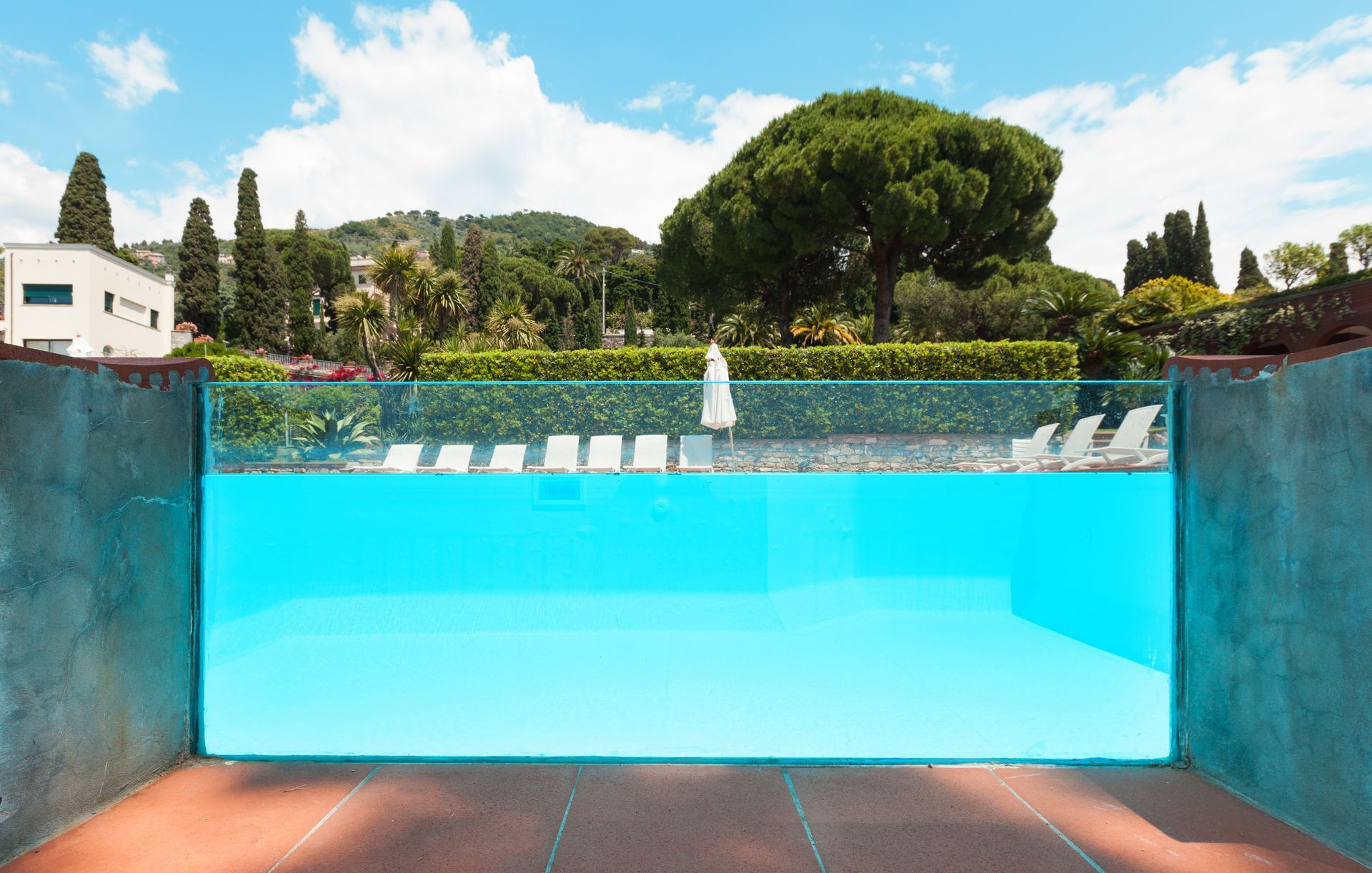 Blue Swimming Pool With Clear Glass Wall — All Glass Balustrading Systems in Central Coast, NSW