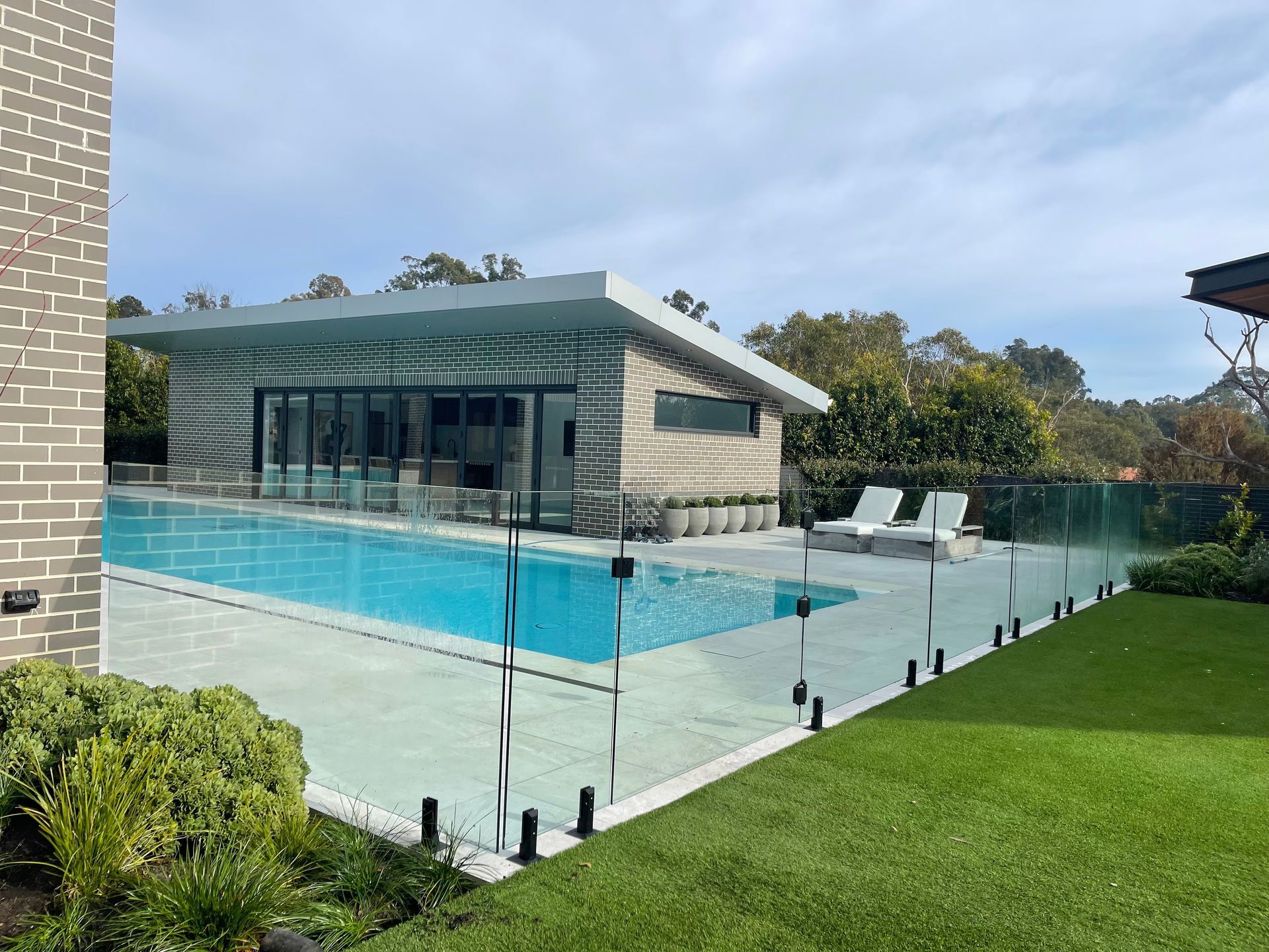 Swimming Pool Area With a Glass Fence, Outdoor Structure, and Lawn — All Glass Balustrading Systems in Wetherill Park, NSW