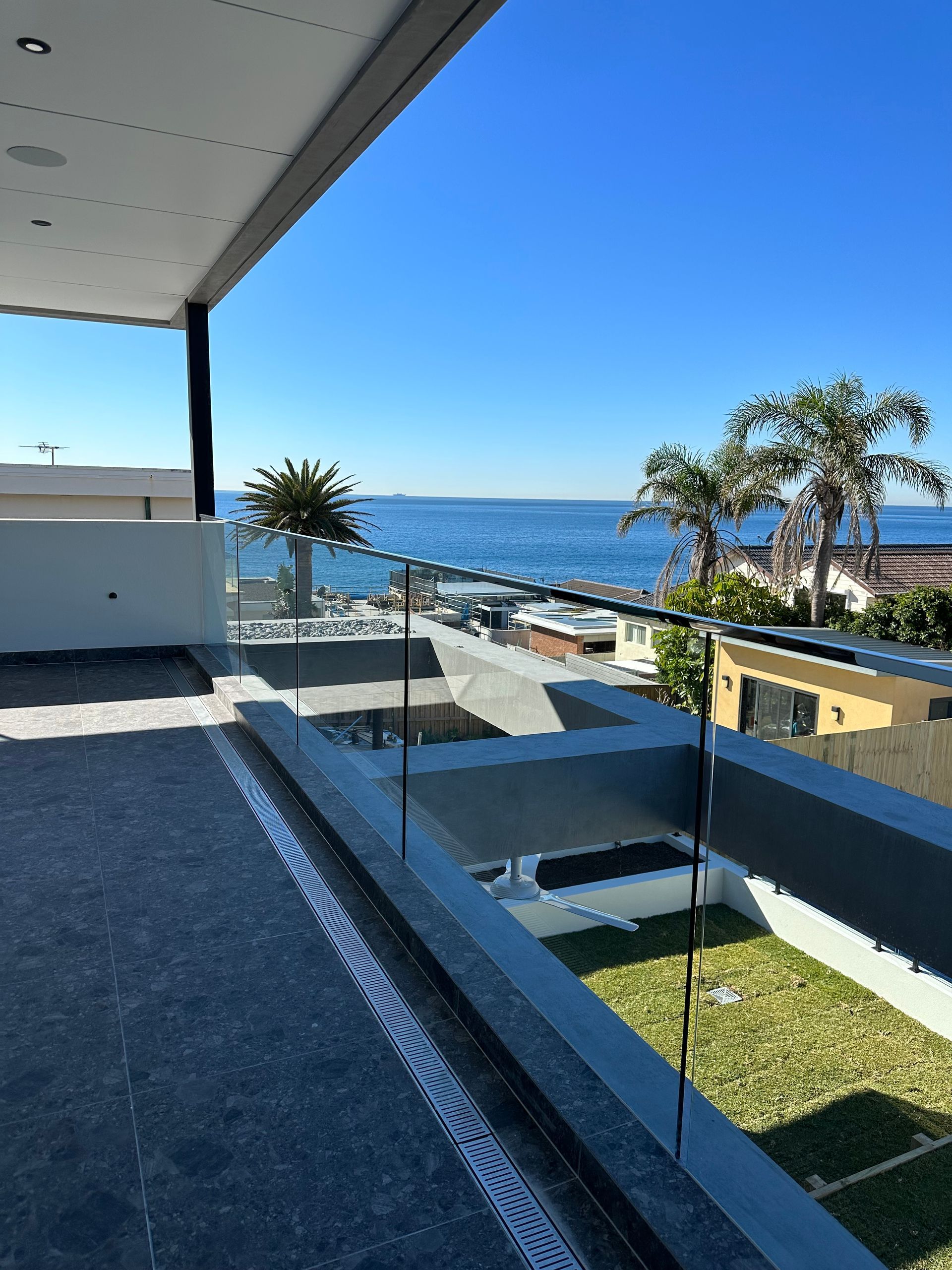 A Balcony With Glass Railings Overlooking The Ocean — All Glass Balustrading Systems in Wetherill Park, NSW