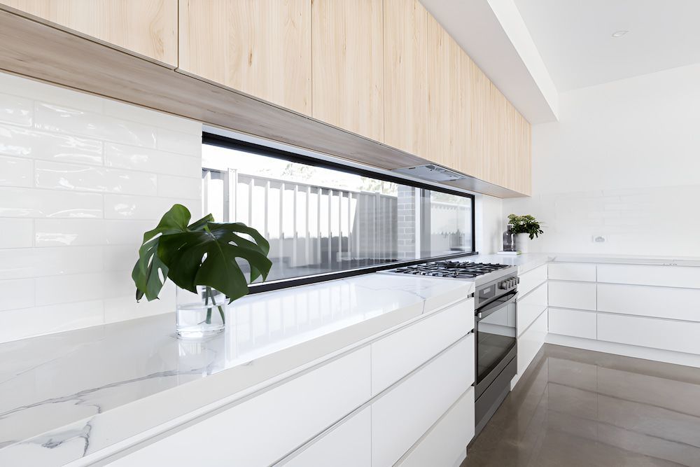 A Kitchen With White Cabinets and a Potted Plant on the Counter — All Glass Balustrading Systems in Wetherill Park, NSW