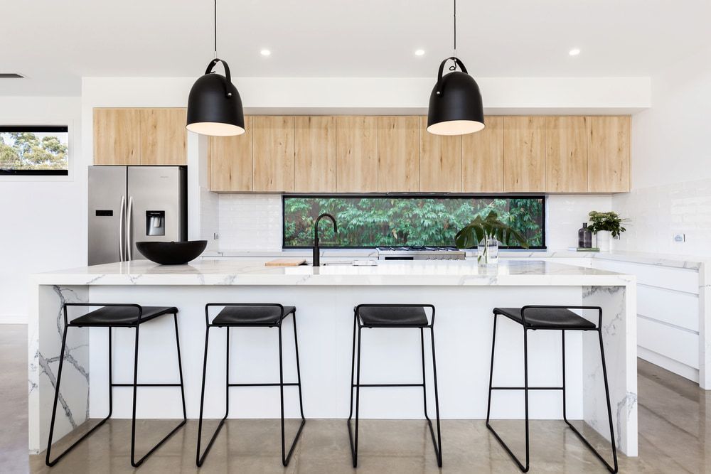 A Kitchen With a Large Island, Stools, and a Refrigerator — All Glass Balustrading Systems in Wetherill Park, NSW
