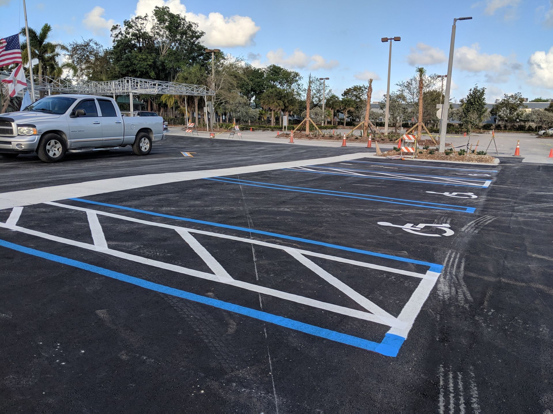 A newly painted accessible parking spot with blue border, white diagonal stripes, and a wheelchair symbol in a parking lot.