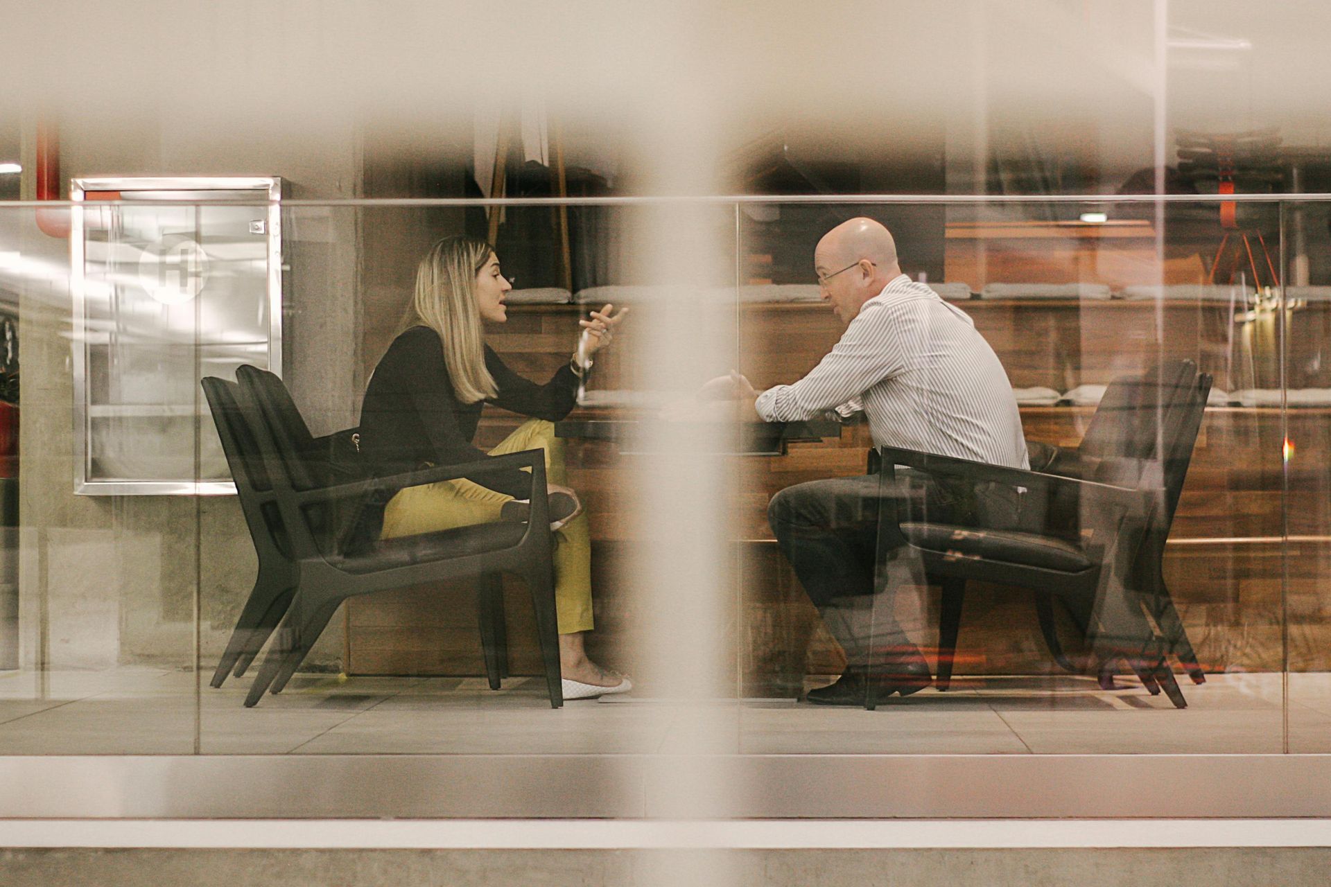 A man and a woman are sitting at a table having a conversation.