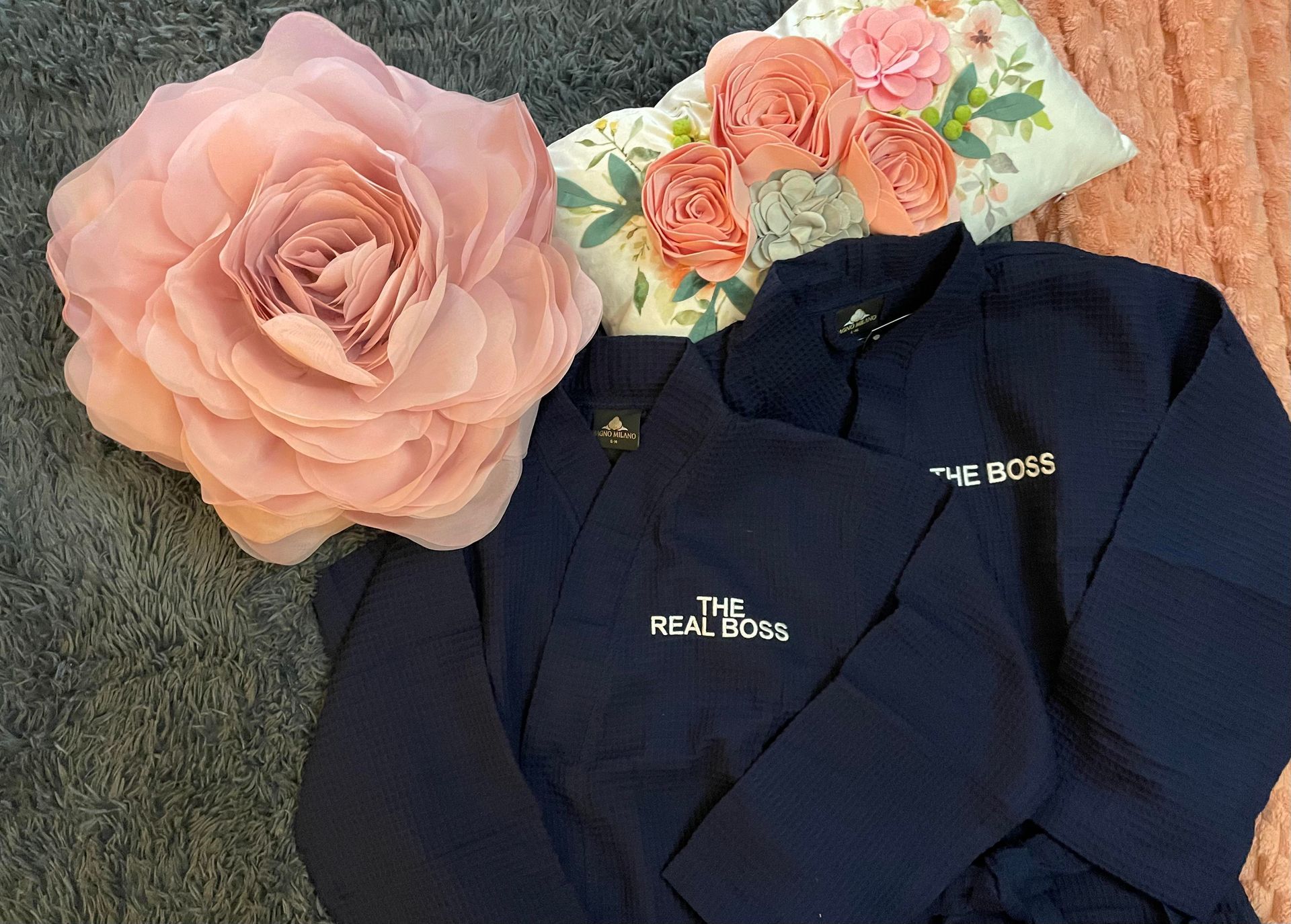 Navy embroidered jacket beside pink flowers and a large blush rose on a gray surface