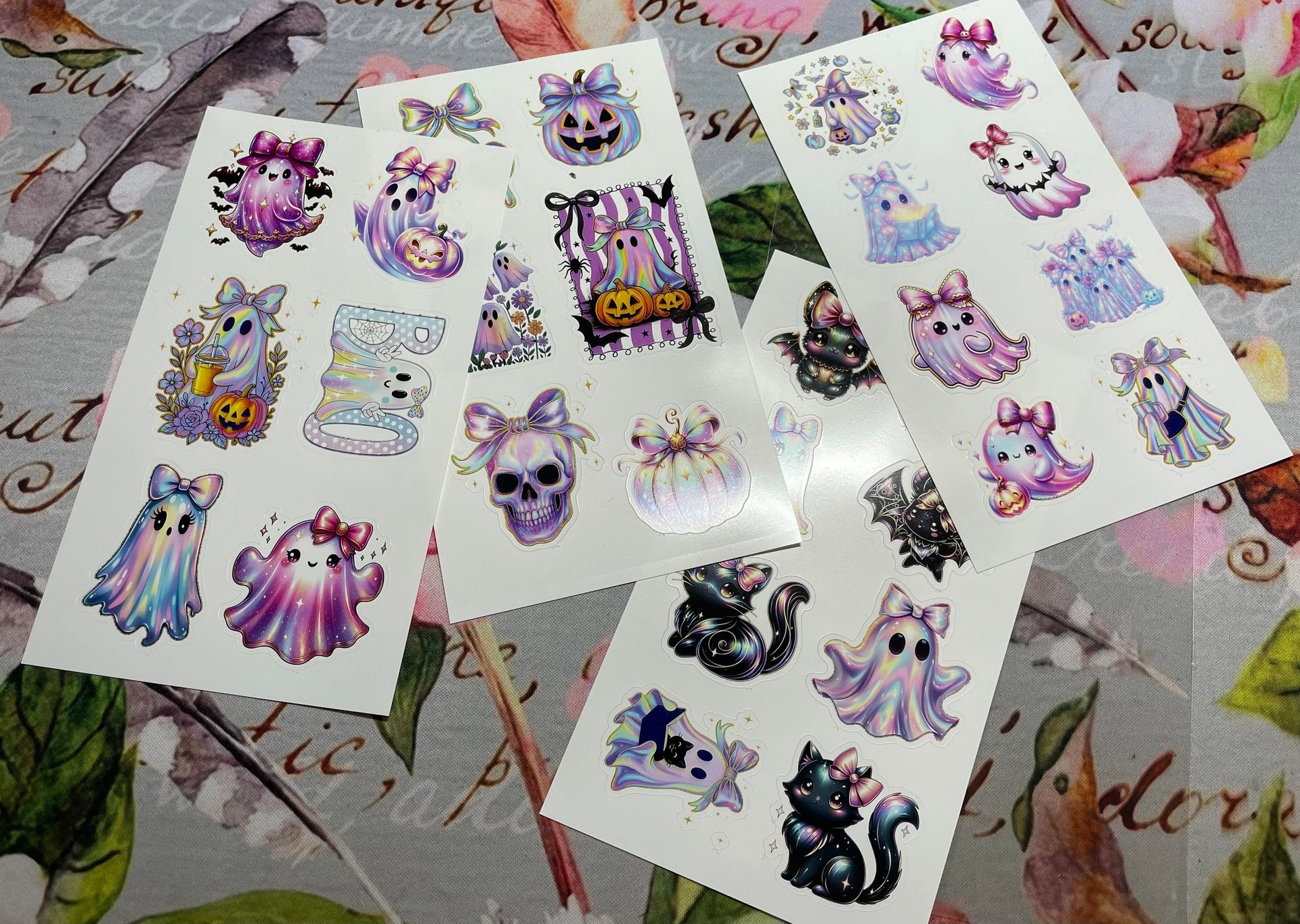 Several sheets of colorful cat stickers spread on a patterned tablecloth