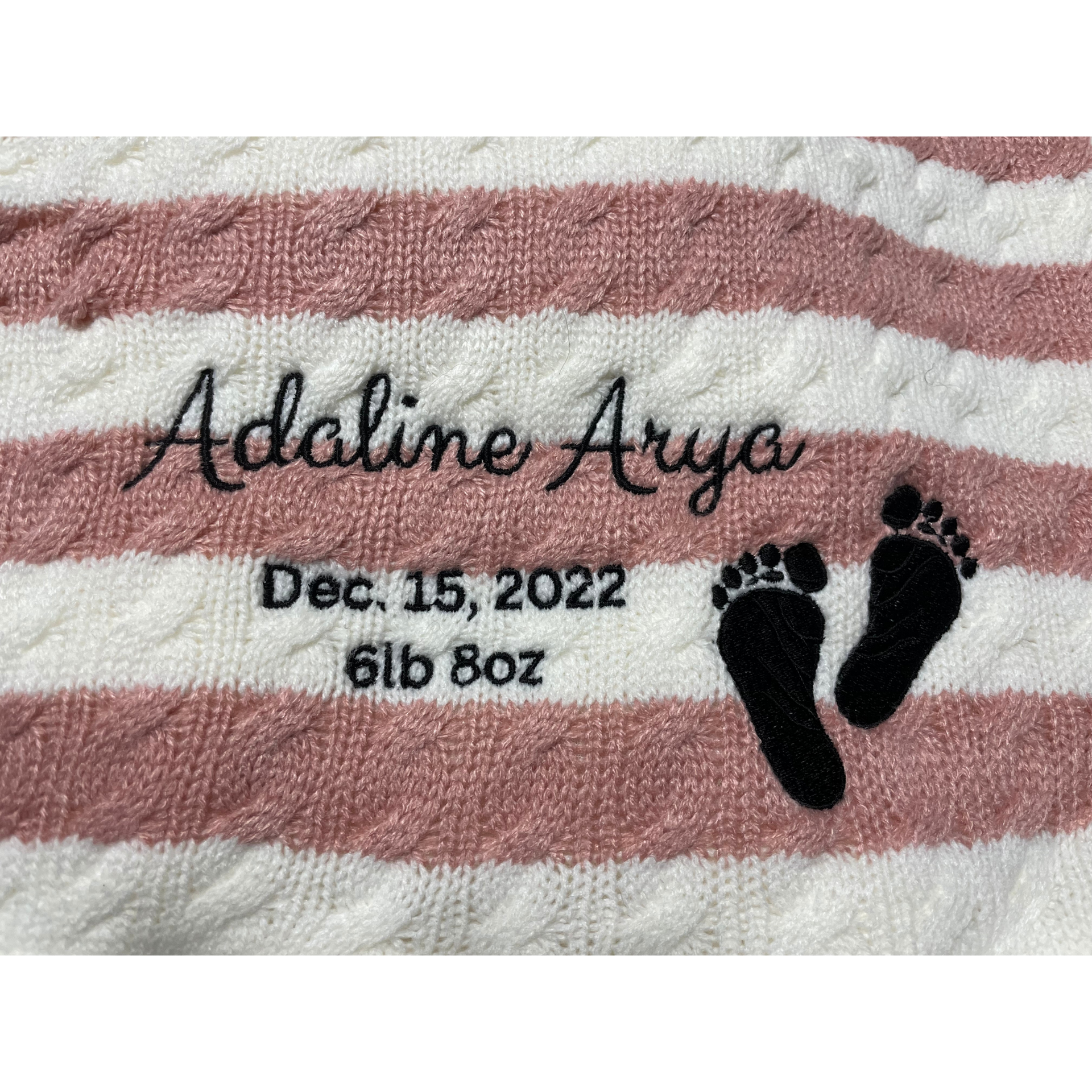 Pink-and-white striped blanket with “Adaline Arya,” birth date, weight, and baby footprints