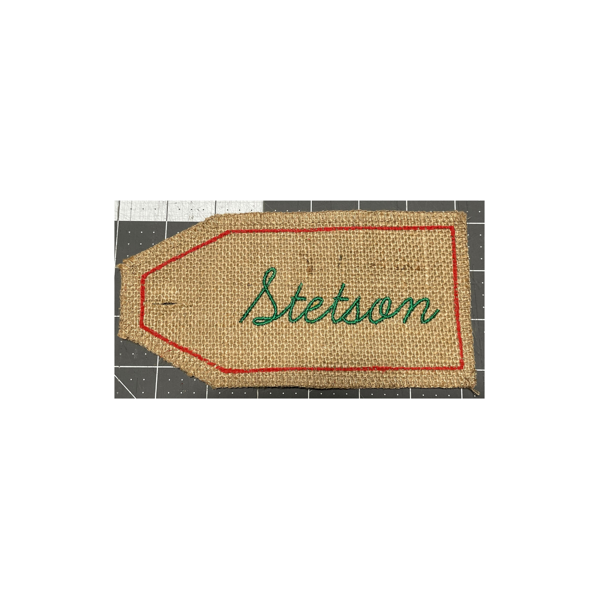 Beige woven name tag with red border and green cursive text reading “Bledan”