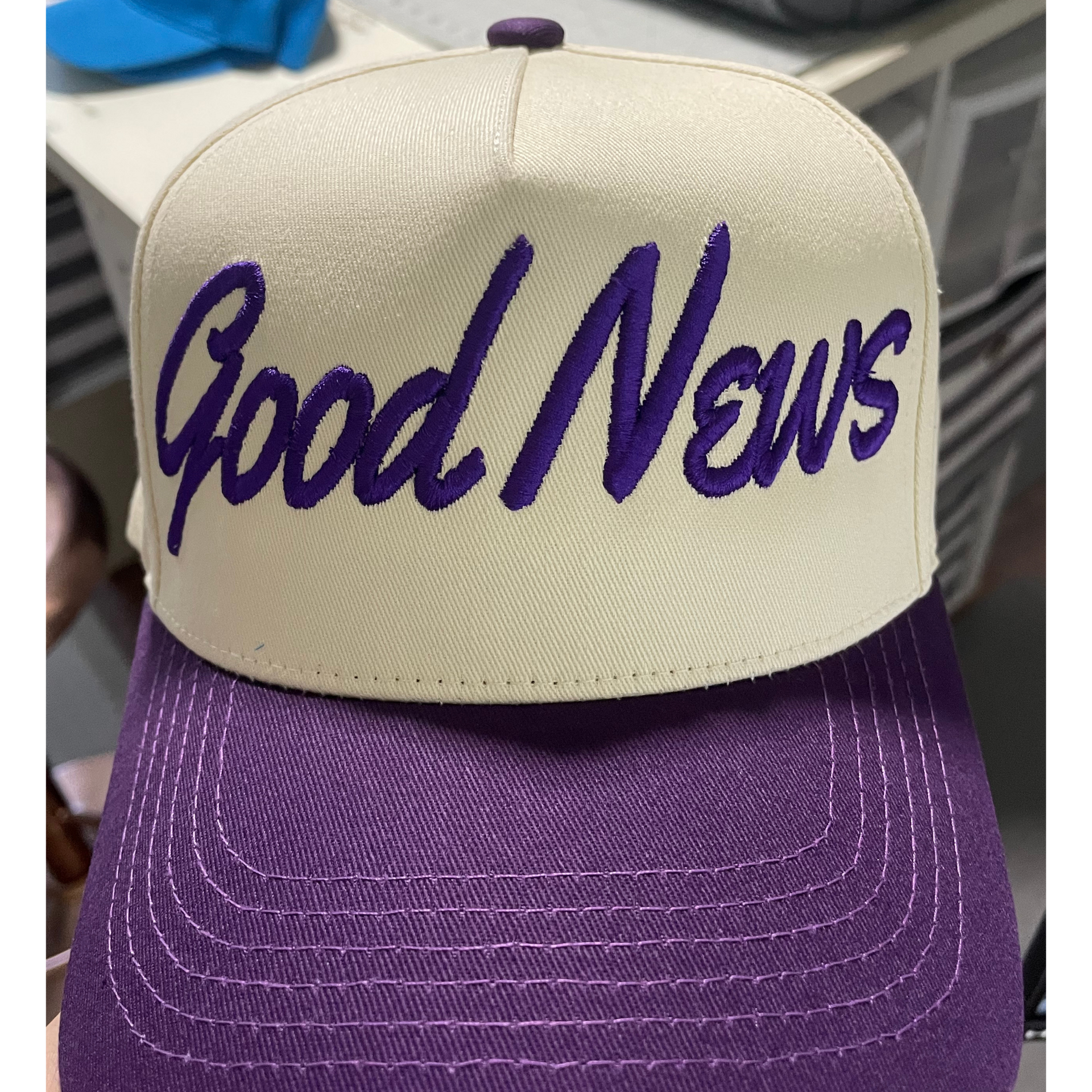 Purple and cream cap with “Good News” text on the front