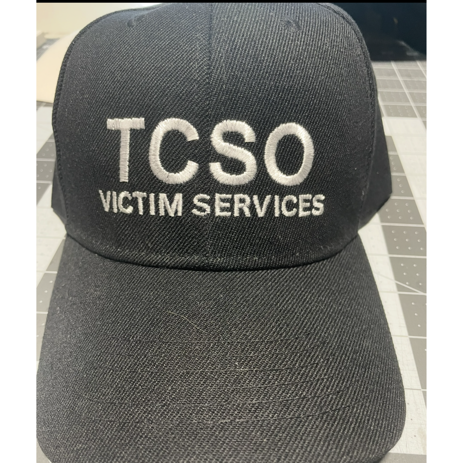 Black cap with “TCSO VICTIM SERVICES” embroidered in white.