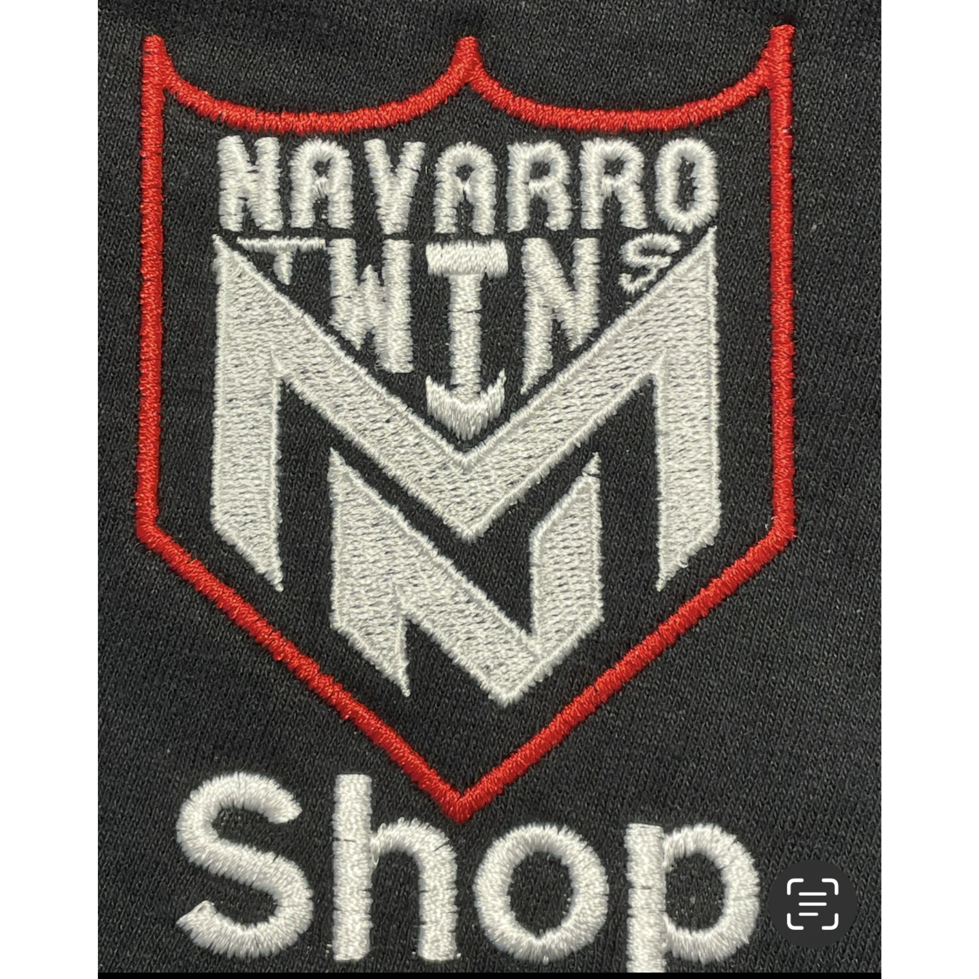 Navarro NTN shop logo patch in white, gray, and red on a dark background