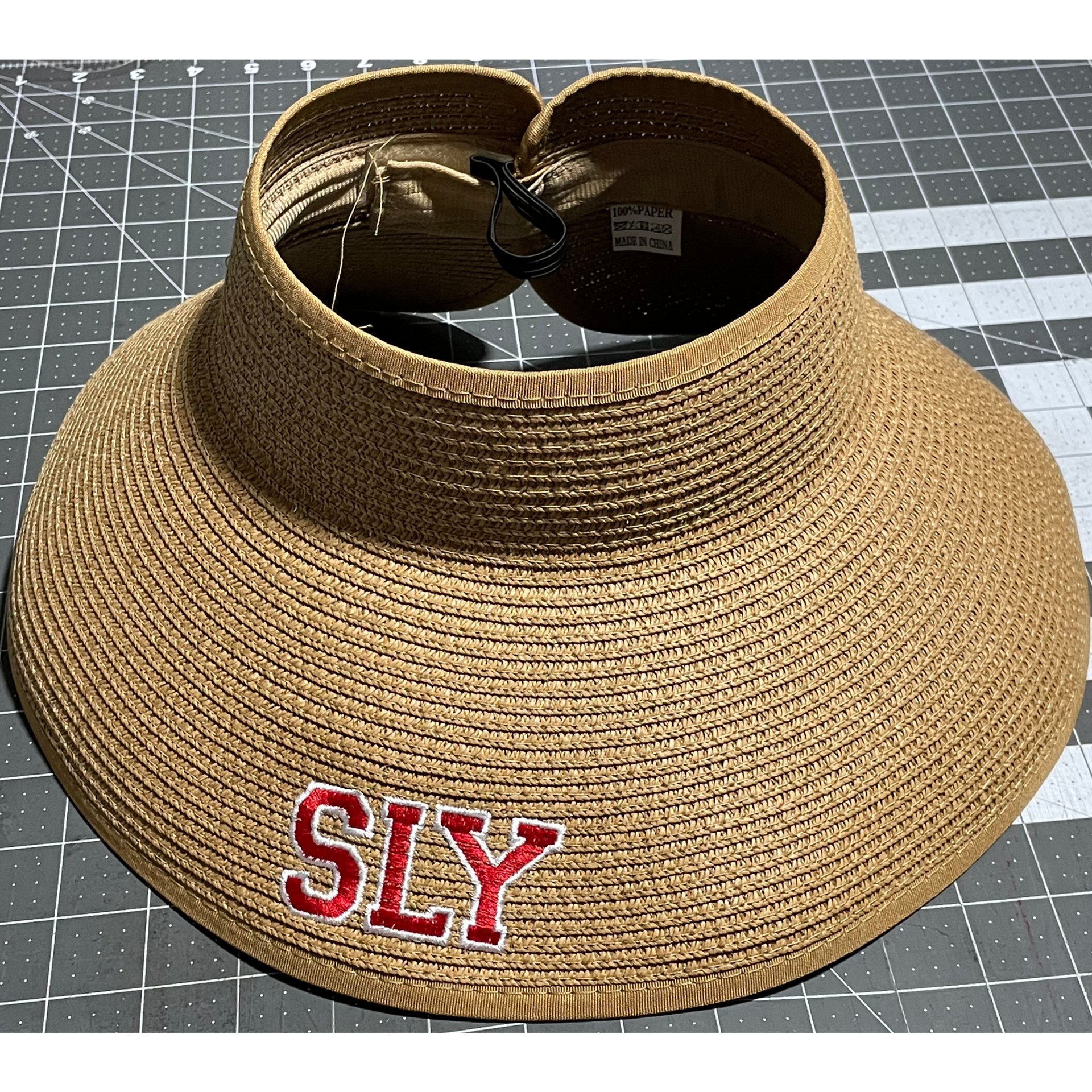 Tan straw visor with red “SLY” lettering on the front