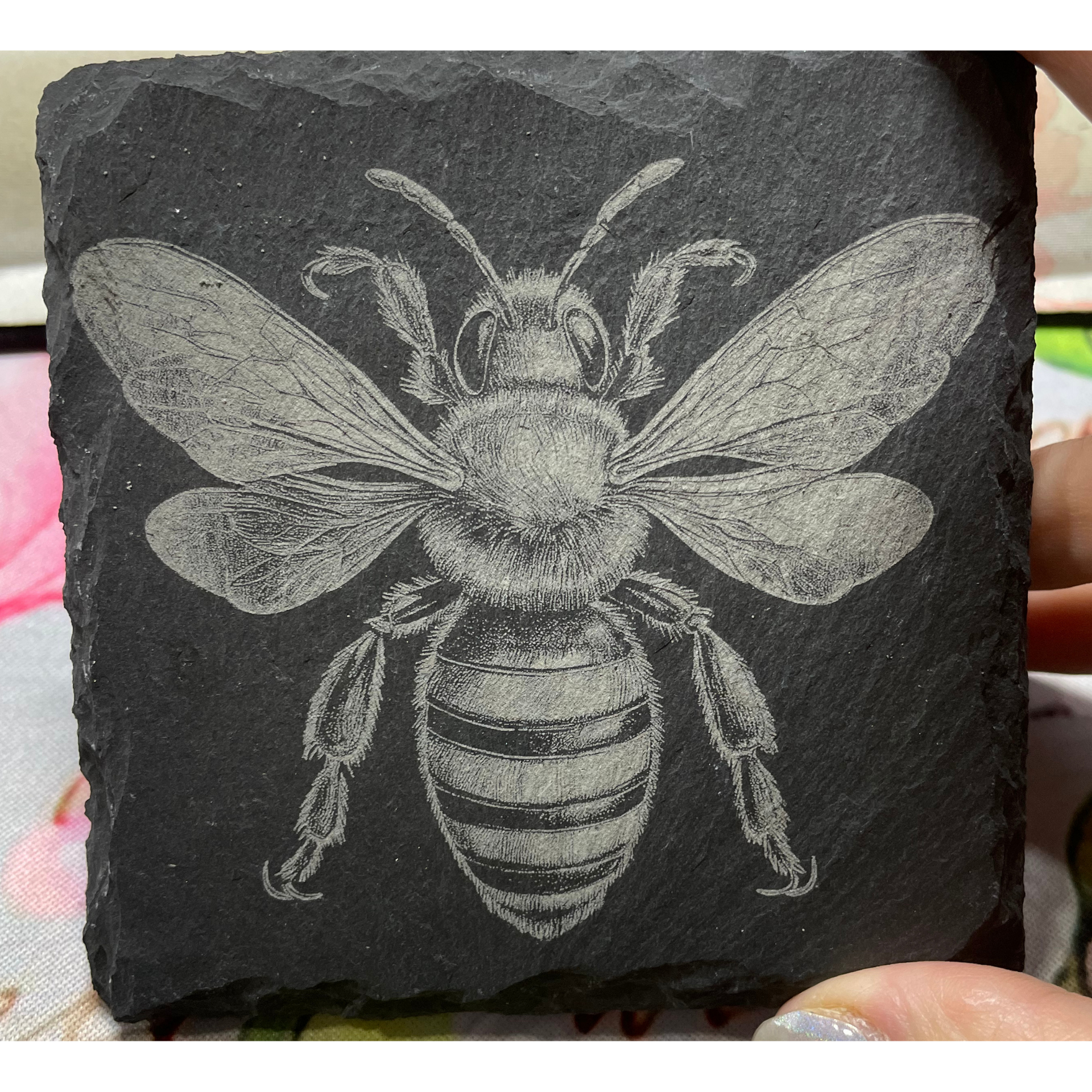 White bee drawing on a black stone tile.