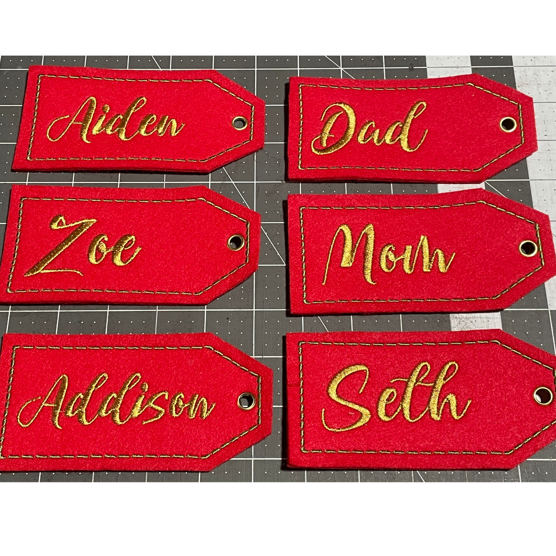 Six red gift tags with gold names: Aiden, Dad, Zoe, Mom, Addison, and Seth