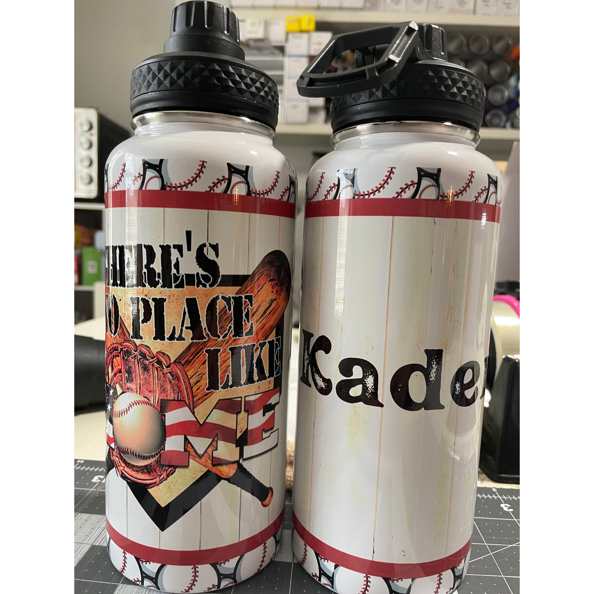 Two white water bottles with black caps and red accents, one labeled “IRE’S PLACE TIME,” the other “Kadel.”
