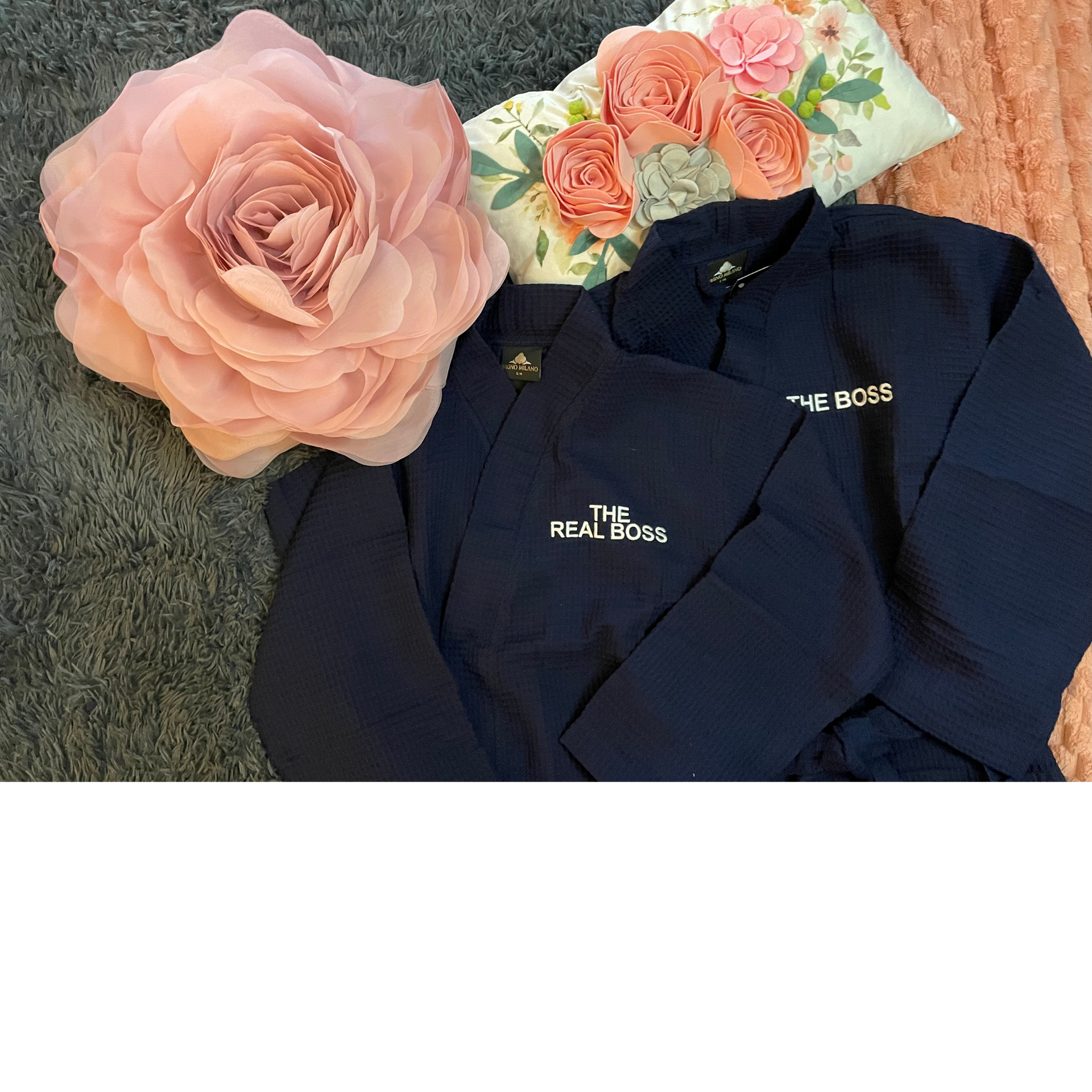 Navy jackets with “The Row” logo, a peach flower, and a floral pouch on a textured gray background