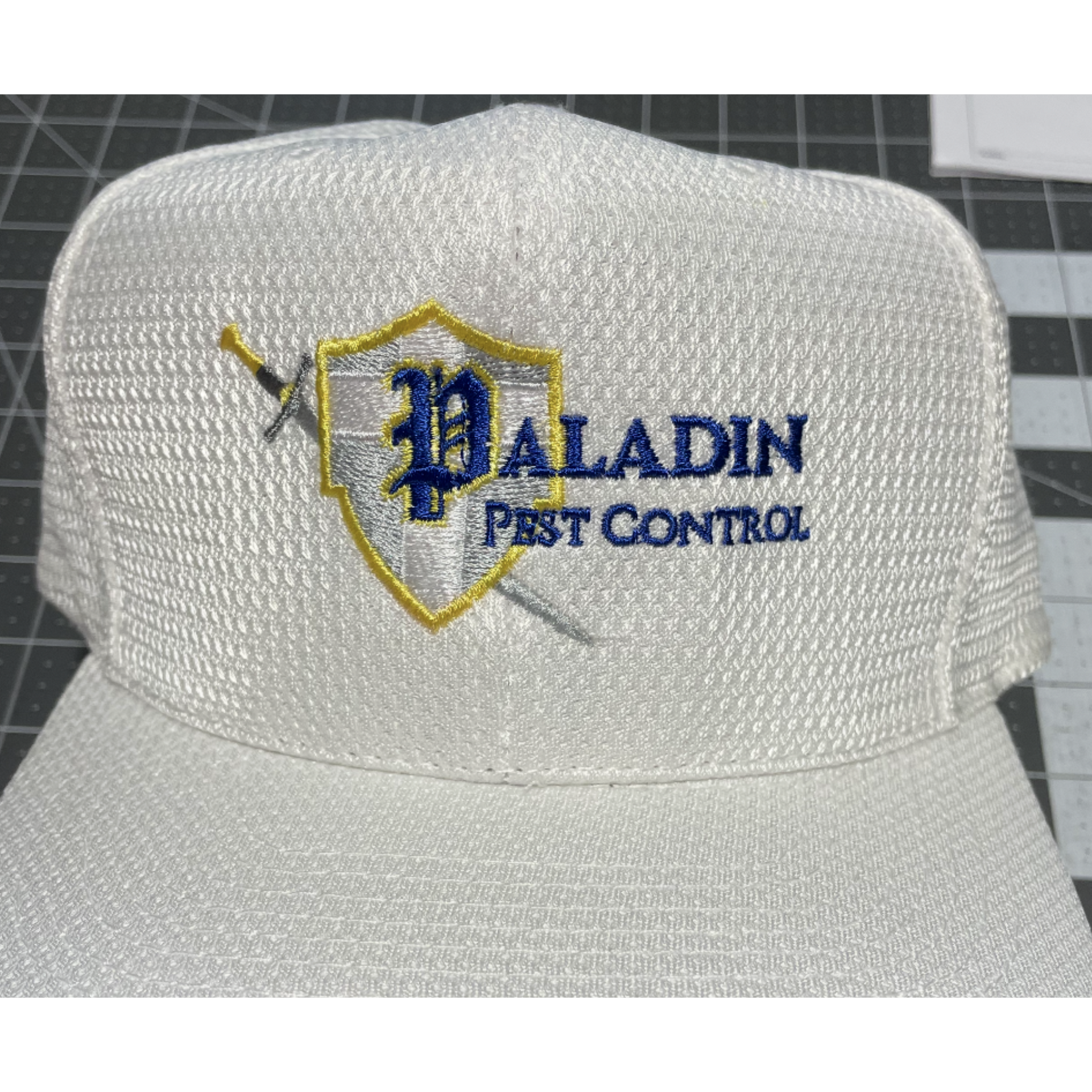 White mesh cap with blue and gold “Paladin Pest Control” logo and shield emblem